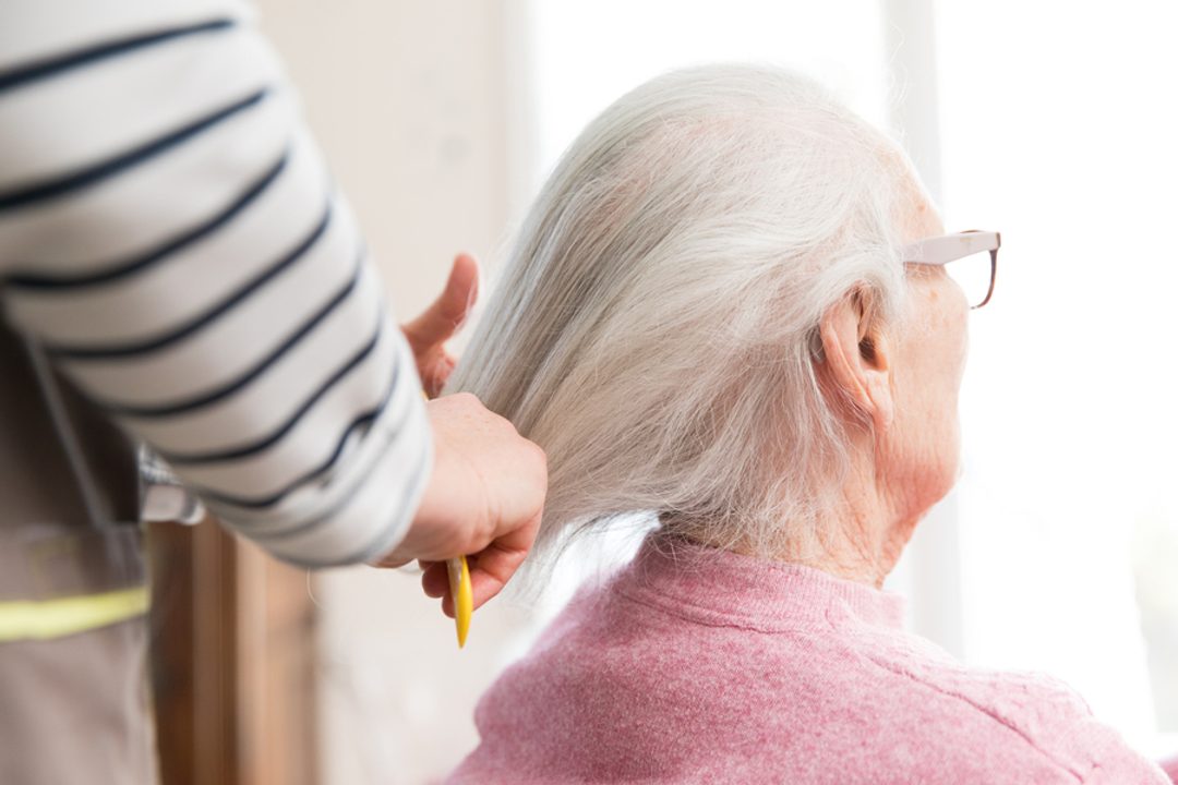 Une dame âgée se fait coiffer.